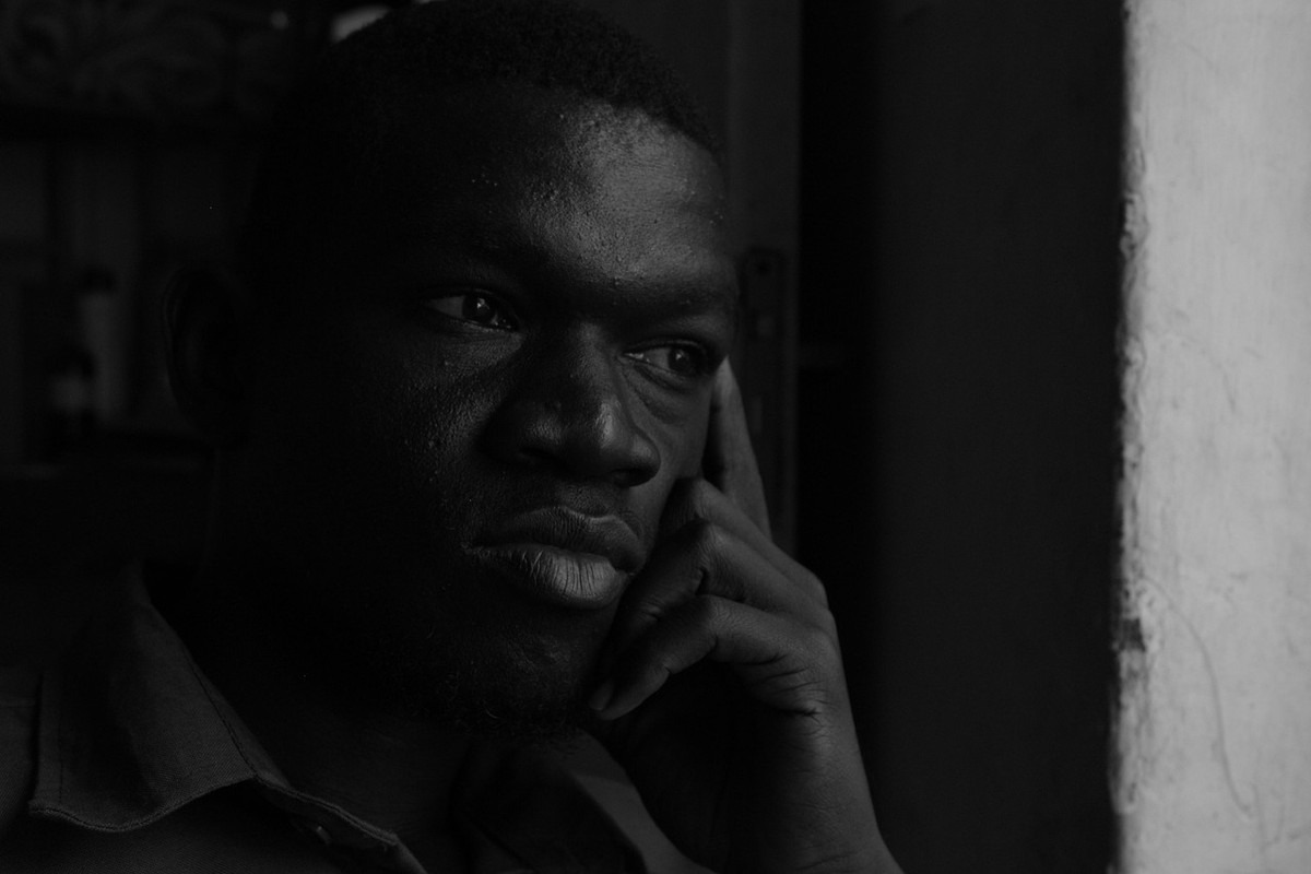 Homme en noir et blanc, main contre la joue, expression préoccupée et réfléchie