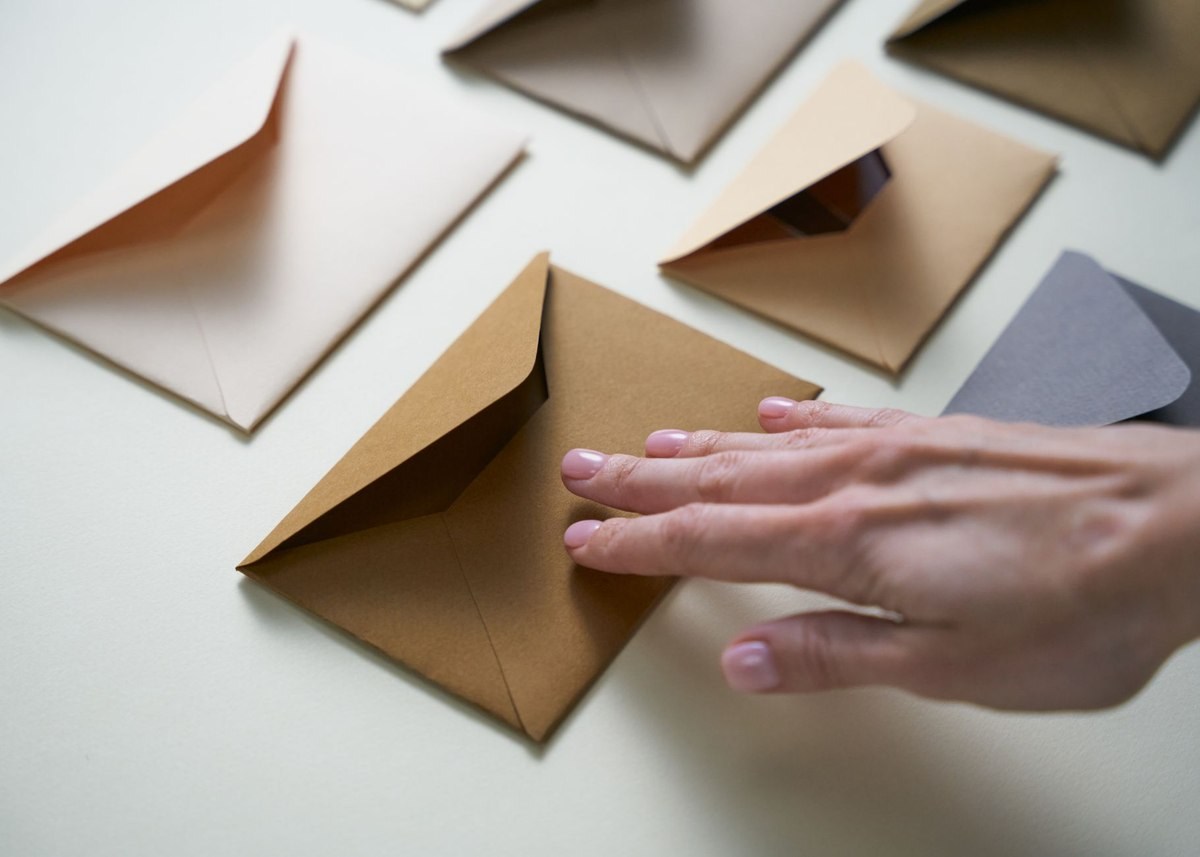Une main pose doucement une enveloppe marron sur une surface claire