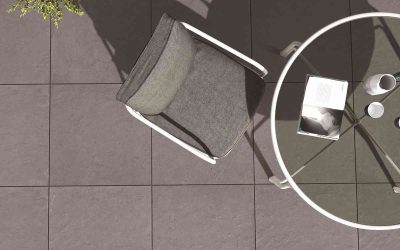Chaise grise, table ronde, livre et tasse sur sol carrelé