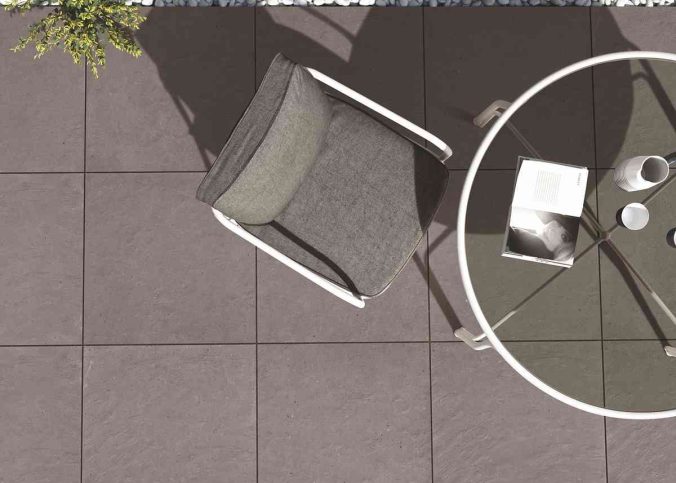 Chaise grise, table ronde, livre et tasse sur sol carrelé